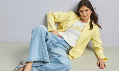 een vrouw in een gele blazer en lichte jeans liggend op de grond