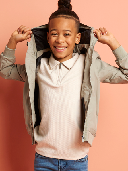 jongen met verstelbare taille jeans, een beige rits polo en groene jas