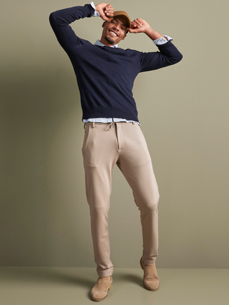 man in een beige chino broek en een donkerblauwe trui