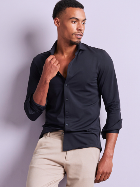 man met een donkerblauw overhemd en een beige broek