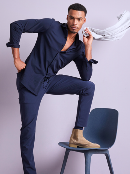 man poserend met een donkerblauw overhemd en een donkerblauwe broek