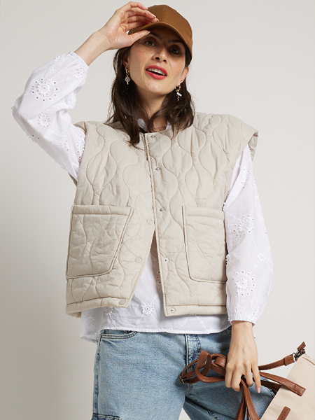 vrouw met witte blouse en beige gilet